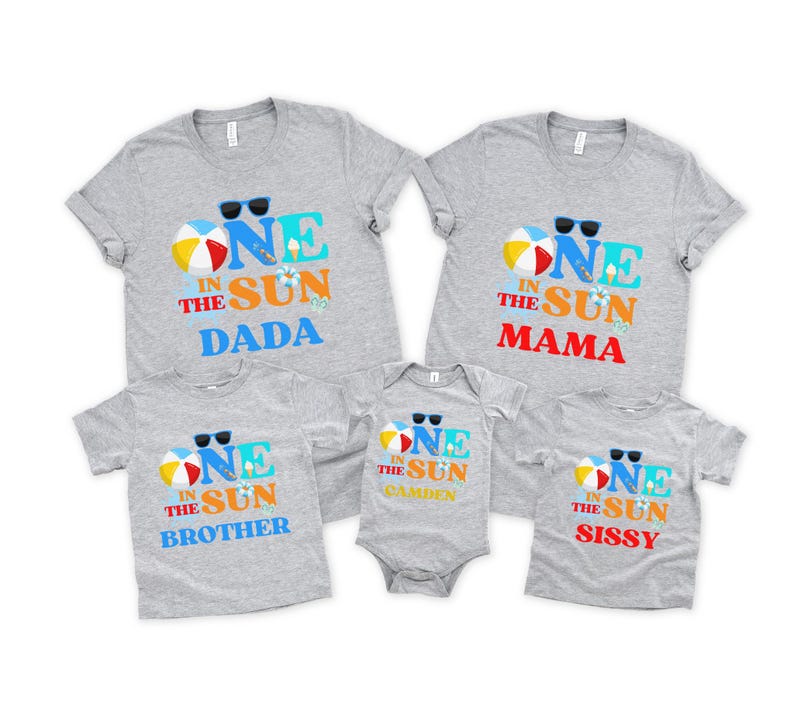 Puede incluir: Un conjunto de cinco camisetas y un body de color gris jaspeado con un gr&aacute;fico de tem&aacute;tica playera y el texto ONE IN THE SUN. Cada prenda incluye ilustraciones de una pelota de playa, gafas de sol y helado, con las etiquetas DADA, MAMA, BROTHER, SISSY y CAMDEN.