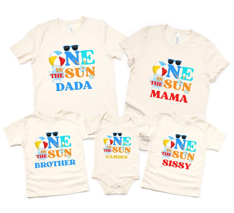Puede incluir: Un conjunto de cinco camisetas y un body de color crema con un estampado gr&aacute;fico que dice ONE IN THE SUN junto a una pelota de playa, gafas de sol y un helado. Las prendas incluyen las palabras DADA, MAMA, BROTHER, SISSY y CAMDEN.