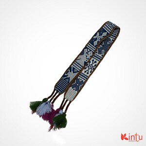 Könnte beinhalten: Ein gewebtes Alpaka-Band mit weißem und blauem Muster, braunem Besatz und bunten Quasten. Das Band ist etwa 3,8 cm breit und hat ein geometrisches Muster.