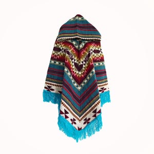 May include: A hooded poncho featuring a vibrant woven pattern in shades of teal, burgundy, cream, and brown. The garment displays a symmetrical chevron design with geometric motifs and is finished with a bright teal fringe along the bottom edge.