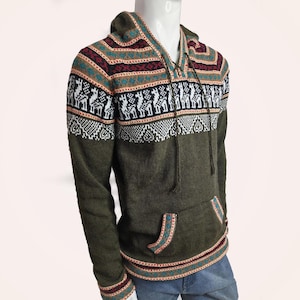 Könnte beinhalten: Ein olivgrüner Kapuzenpullover mit langen Ärmeln und einem Strickmuster aus weißen Lamas auf der Brust. Das Kleidungsstück verfügt über eine Kängurutasche, eine Kapuze mit Kordelzug und dekorative Bänder mit roten, weißen und türkisfarbenen geometrischen Mustern.