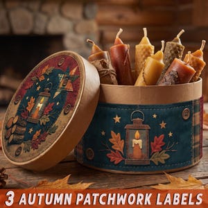 May include: A round cardboard box with a lid, decorated with a dark blue patchwork-style print featuring lanterns, autumn leaves, and buttons. Inside the box are several taper candles in shades of brown, yellow, and orange, some with textured surfaces.