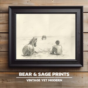 May include: A black and white pencil drawing of a boy sitting in a field with a horse and two other horses in the distance. The drawing is framed in a black frame.