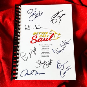 Può includere: Una pagina bianca con una rilegatura a spirale nera. La pagina ha il titolo "Better Call Saul" con un logo giallo e il testo "Stagione 6 - Episodio 13 - Saul Gone." La pagina è firmata dal cast e dalla troupe, tra cui Rhea Seehorn, Patrick Fabian, Bob Odenkirk, Michael Mando, Peter Gould e Bryan Cranston.
