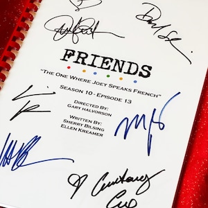 May include: A white script with the title "FRIENDS" and the episode title "THE ONE WHERE JOEY SPEAKS FRENCH". The script is signed by multiple people in black and blue ink. The script is bound with a red spiral.