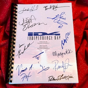 May include: A white script with the title "Independence Day" and the names of the director and writer, Roland Emmerich and Dean Devlin, is signed by multiple people in blue ink. The signatures include "Jeff Goldblum", "Bill Pullman", "Vivica A. Fox", "Randy Quaid", "Margaret Kidder", "Robert Loggia", and "Will Smith".