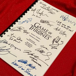 Peut inclure: Une page de script blanche du premier épisode de la série télévisée Game of Thrones, signée par les acteurs et l'équipe. Le titre de l'épisode est "Winter is Coming".