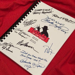 Könnte beinhalten: Ein weißes Notizbuch mit einer schwarzen Spiralbindung. Der Umschlag zeigt eine Schwarzweißillustration einer Figur aus dem Film "Nightmare on Elm Street". Das Notizbuch ist von mehreren Personen signiert, darunter der Regisseur Wes Craven. Der Text "Don't Fall Asleep!!" ist in schwarzer Farbe auf dem Umschlag geschrieben.