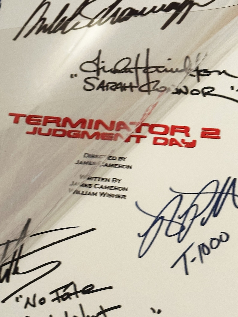 Pu&ograve; includere: Un poster bianco con il titolo "Terminator 2: Il Giorno del Giudizio" in rosso. Il poster ha diverse firme, tra cui quella di Linda Hamilton, che ha firmato il suo nome come "Sarah Connor".