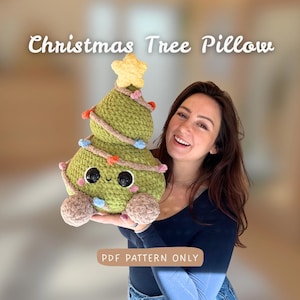 Könnte beinhalten: Ein grünes, gehäkeltes Weihnachtsbaumkissen mit Stern, Lichtern und einem lächelnden Gesicht. Das Kissen hat braune Akzente und der Text "Christmas Tree Pillow" ist oben abgebildet. Der Text "PDF PATTERN ONLY" ist unten abgebildet.
