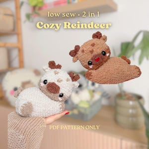 May include: Two plush reindeer toys made of textured yarn, one in cream and one in brown. Each features small antlers, dark round eyes, and a small nose. The text reads: low sew 2 in 1 Cozy Reindeer and low PDF PATTERN ONLY.