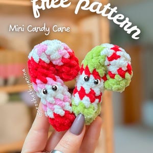 May include: Two mini crochet candy canes in red, pink, white, and green. The candy canes have googly eyes and are held in a hand. Text on the image says "free pattern", "Mini Candy Cane", and "NO SEW".