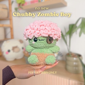 Pode incluir: Um brinquedo de pelúcia de crochê intitulado no sew Chubby Zombie Boy, com corpo verde claro, topo rosa texturizado semelhante a um cérebro, um olho preto e um olho de botão marrom. A parte inferior é bege, com o texto PDF PATTERN ONLY.