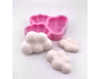 May include: Pink silicone mold with three cloud-shaped cavities. Three white cloud-shaped objects are shown next to the mold.