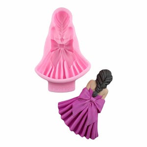 Puede incluir: Molde de silicona rosa de una niña con un gran lazo en el pelo y un vestido con un gran lazo en la espalda. El molde está sobre un fondo blanco. La niña lleva un vestido morado.