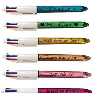 Puede incluir: Una colección de bolígrafos personalizados con barriles metálicos y detalles blancos. Cada bolígrafo presenta una inscripción diferente en negro, incluyendo frases como "Arrière grand père" y "Merci pour tout".