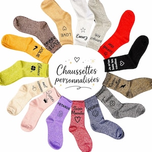 Può includere: Una collezione di calzini glitterati in vari colori, tra cui oro, argento, rosso e nero. Ogni calzino presenta un design o un testo unico, come cuori, stelle e frasi come "Love" e "Queen". I calzini sono disposti in un motivo circolare.