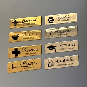 Peut inclure: Huit étiquettes de nom dorées avec du texte noir et des icônes. Les noms sont Edouard, Sylvie, Marina, Alexandre, Romane, Arnaud, Laura et Amanda. Les icônes sont un mortier et un pilon, une empreinte de patte, une paire de ciseaux, un bonnet de graduation, une croix, un stéthoscope et un pinceau à maquillage.