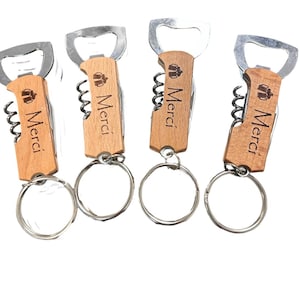 May include: Four wooden bottle openers with keyrings. Each opener has a corkscrew, bottle opener, and a small knife. The wooden handles are engraved with the word "Merci".