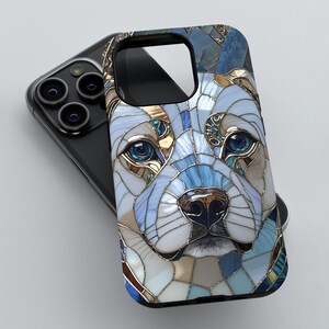 May include: A phone case with a stained glass design of a dog's face. The dog has blue eyes and a white, blue, and gold patterned face.