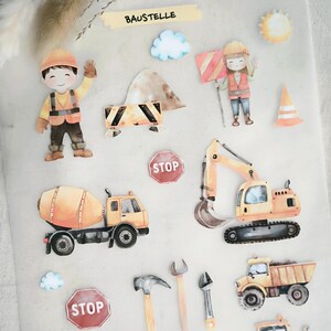 Op de afbeelding: Stickers met een bouwthema met illustraties van bouwvakkers, voertuigen en gereedschappen. De stickers bevatten een betonmixer, graafmachine, bulldozer en een bord met "STOP". Het kleurenpalet omvat geel, oranje en blauw.