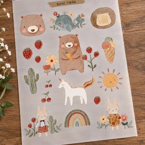Könnte beinhalten: Ein transparenter Aufkleberbogen mit der Aufschrift BOHO TIERE, der Aquarellillustrationen eines Bären, eines Wals, eines Einhorns, zweier Hasen, eines Kaktus, einer Sonne, einer Eistüte, Erdbeeren, Kirschen, Blumen und eines Regenbogens auf grauem Grund zeigt.