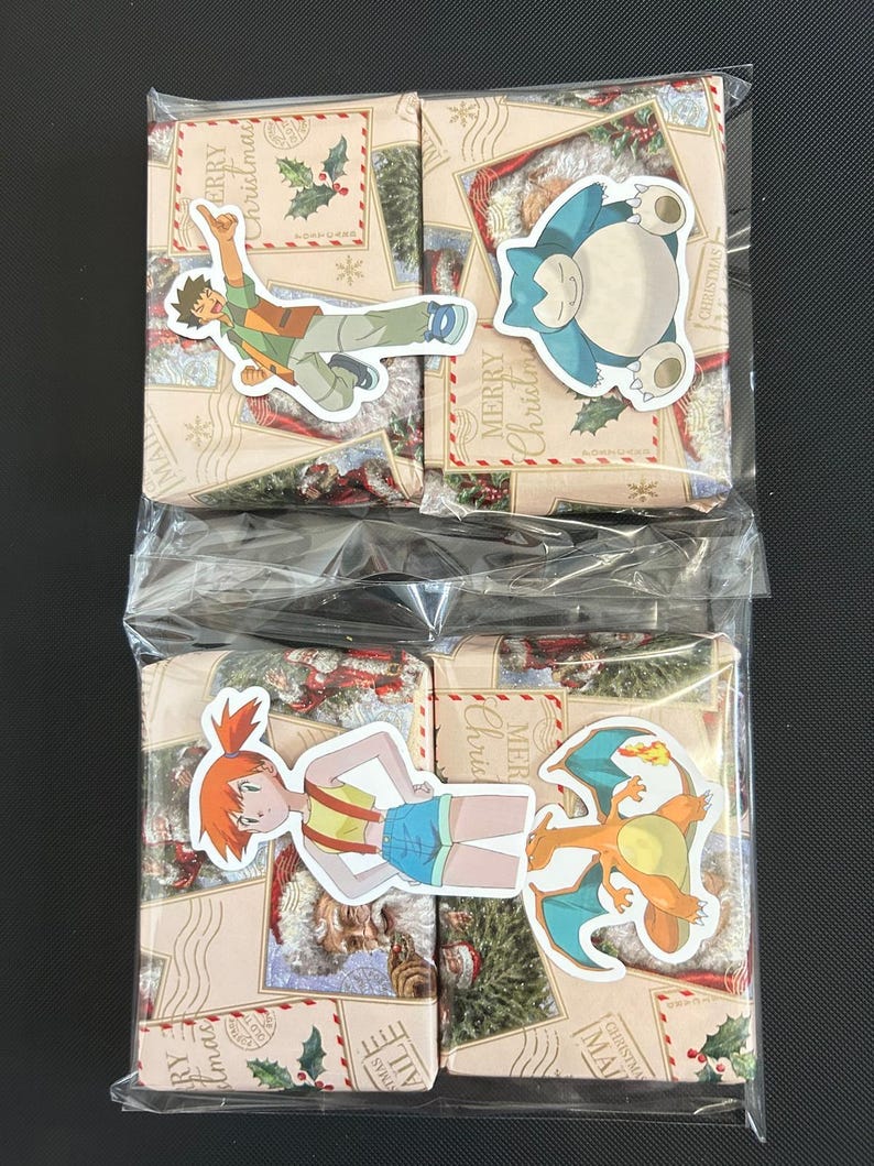 May include: Two wrapped gift boxes with Pokemon character stickers. The boxes have a Christmas theme with "Merry Christmas" text and illustrations. One box has a sticker of Misty, and the other has a sticker of Charizard.