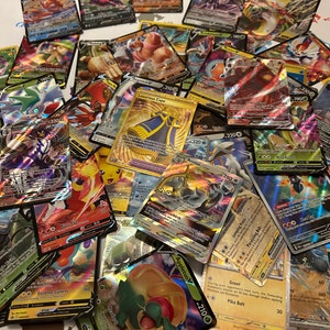 May include: A pile of Pok&eacute;mon trading cards with vibrant illustrations and text. Several cards have gold detailing and text such as "Luxurious Cape" and "Arceus". The cards are spread out on a light-coloured surface.