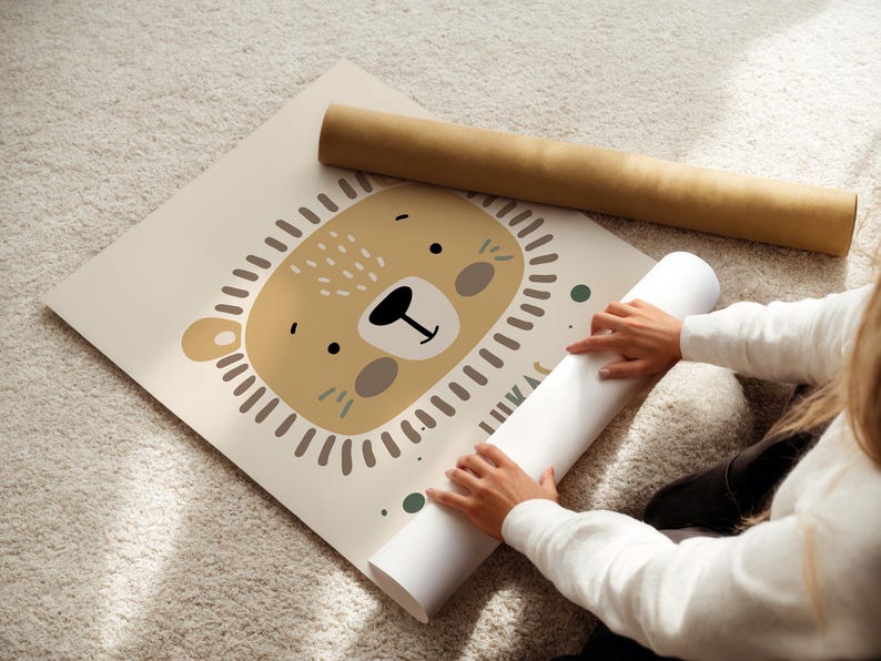 May include: A beige poster with a cartoon illustration of a lion's face. The lion has a brown nose, brown eyes, and a brown mane. The poster is rolled up and being held by a person.