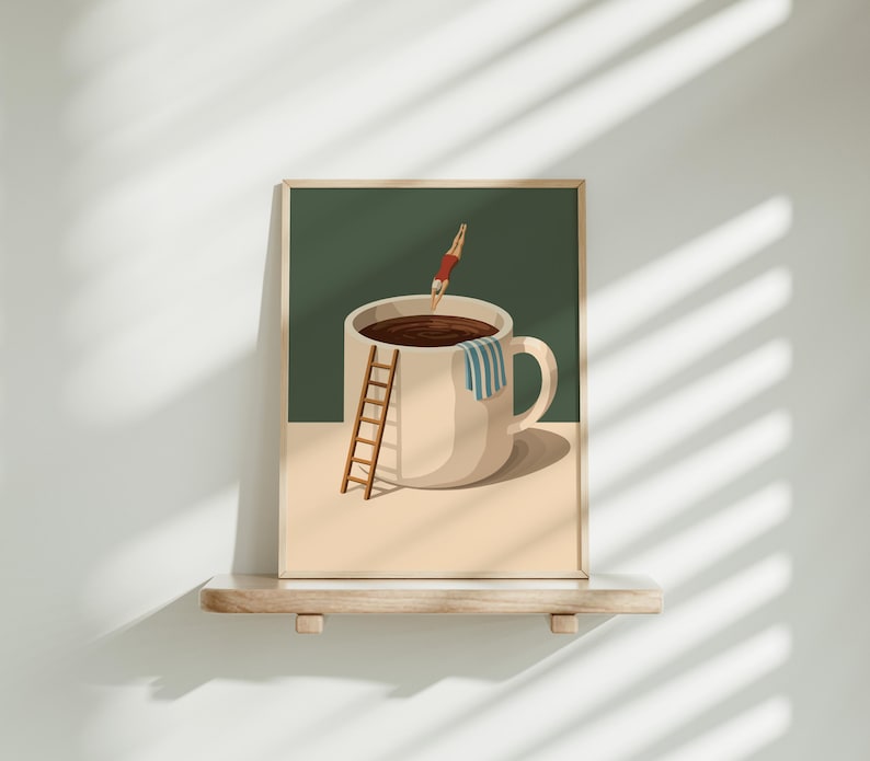 May include: A framed art print depicts a large coffee cup filled with dark liquid. A person in a red swimsuit dives into the cup. A small wooden ladder leans against the cup, and a blue and white striped towel hangs on the handle.