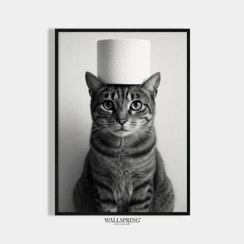 May include: Black and white framed print featuring a tabby cat with a roll of toilet paper balanced on its head. The cat is centered, looking directly at the viewer. The print has a minimalist aesthetic and includes the text "WALLSPRING art for your walls".
