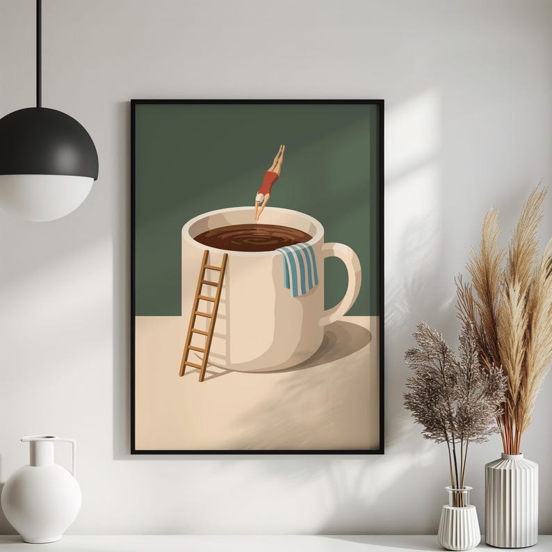 May include: A framed art print depicts a whimsical scene of a person diving into a coffee-filled mug. A wooden ladder leans against the mug, and a striped towel hangs on the handle. The diver wears a red swimsuit. The background is a muted green.
