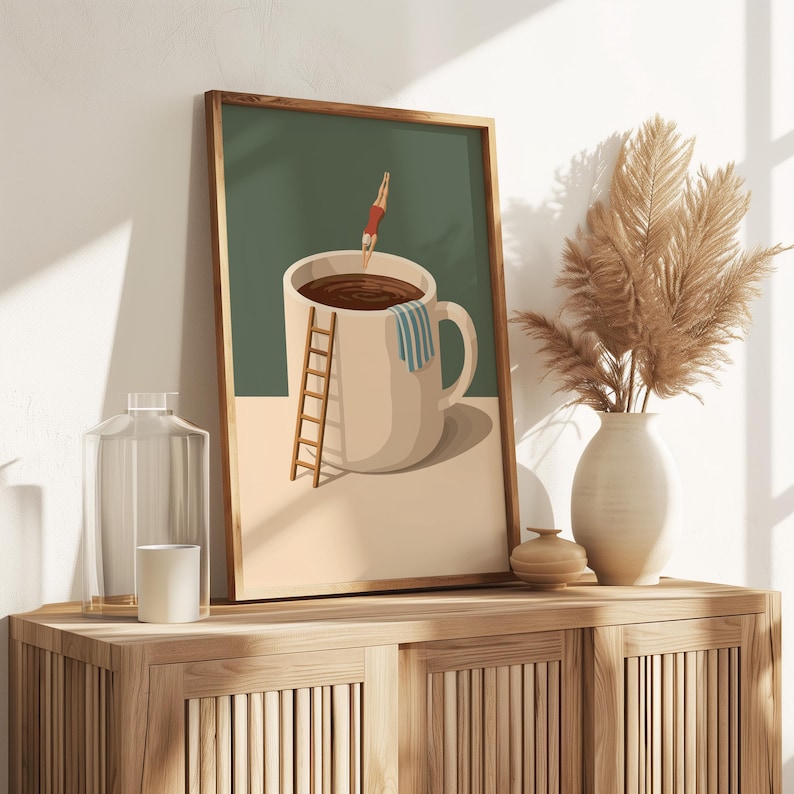 May include: Framed art print featuring a whimsical illustration of a person diving into a coffee cup. The artwork includes a ladder, a towel, and a green and beige color scheme. The print is displayed on a wooden cabinet.
