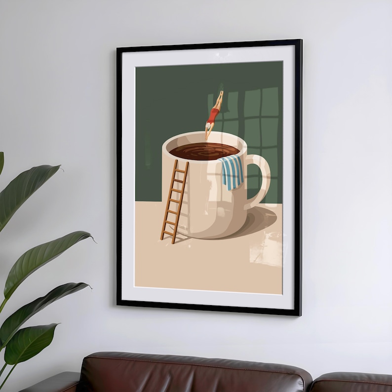 May include: A framed art print depicts a whimsical scene of a person diving into a giant coffee mug filled with dark liquid. A small wooden ladder leans against the mug, and a striped towel hangs on the handle. The background is a muted green.