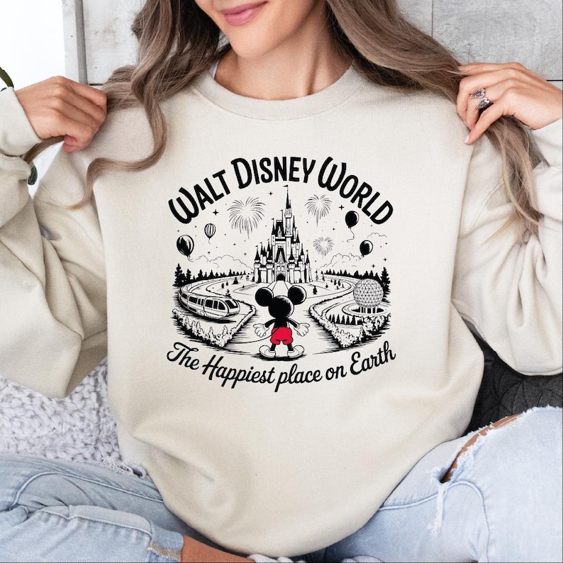 A woman wearing a white sweatshirt with a graphic design of a Disney castle and fireworks.