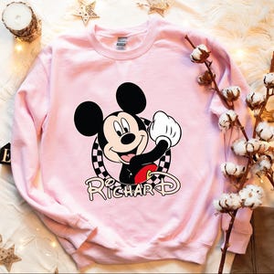 a pink sweatshirt with a mickey mouse on it