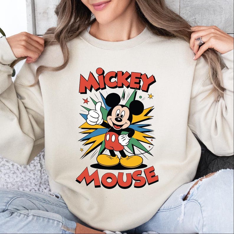 A woman wearing a white sweatshirt with a Mickey Mouse graphic printed on it.