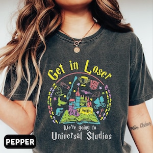 May include: A black t-shirt with a colorful graphic design featuring a castle, a book, a wand, and the text "Get in Loser, We're going to Universal Studios".