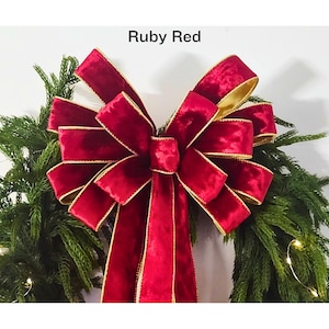 May include: A large, ruby red velvet bow with gold trim, perfect for a Christmas wreath.
