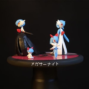 May include: A detailed sculpture of Pokémon characters, including Gardevoir and Ralts, in dynamic poses. The figures are predominantly blue, white, and red, displayed on a round, black and red base. The Japanese text "Mega Knight" is present.