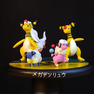 May include: A detailed figurine set featuring several Pokémon characters. The figures include yellow and white creatures with black stripes, a pink creature, and a blue-faced sheep-like figure. The base is black with Japanese text.