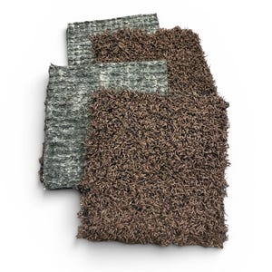 May include: Three textured, rectangular rugs in shades of gray and brown are arranged on a white background. The rugs have a shaggy, tactile appearance, with the brown rug appearing the most plush. The arrangement suggests a display of home decor items.