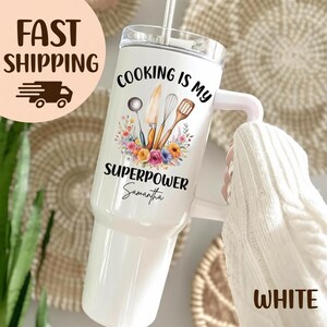 May include: White insulated tumbler with a handle and a straw. The tumbler features the text "COOKING IS MY SUPERPOWER" with a floral design and kitchen utensils. The name "Samantha" is also printed on the tumbler.