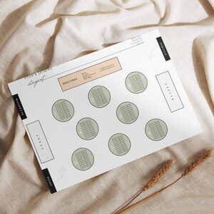 Puede incluir: Un plano de asientos de boda blanco con círculos verdes etiquetados con números. El plano incluye secciones para la mesa principal, el escenario, el buffet y el baño. El texto "Evan & Jasmine Layout" está en la parte superior del plano.