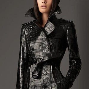 Peut inclure: Un trench-coat en cuir noir à effet croco, avec une fermeture à double boutonnage, une ceinture et un grand col.
