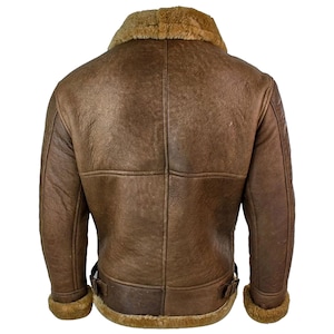 May include: A brown leather jacket with a shearling collar and lining. The jacket has a classic bomber style with a zip closure, two front pockets, and buckle details at the waist. The jacket is made of distressed leather.