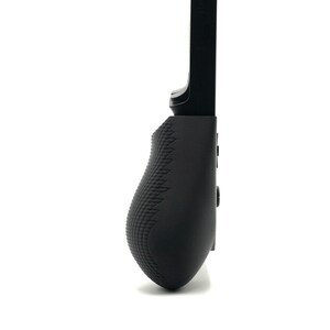 May include: A black gaming controller grip with a textured surface for enhanced grip. The controller grip has a curved design and several buttons. The grip is designed to attach to a mobile device for gaming.