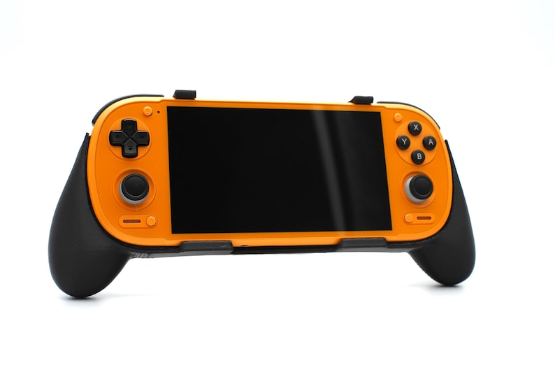 Op de afbeelding: Oranje en zwarte handheld gameconsole met een zwart scherm. Voorzien van een D-pad, knoppen en analoge sticks. De handgrepen zijn zwart, de behuizing oranje. Ontworpen voor draagbaar gamen.