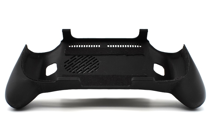 Op de afbeelding: Een zwarte controllerbehuizing met ergonomische handgrepen en een getextureerd oppervlak. De behuizing heeft een ventilatieopening en een reeks kleine gaatjes langs de bovenrand. Het ontwerp is symmetrisch, met een gebogen vorm voor comfortabele bediening.
