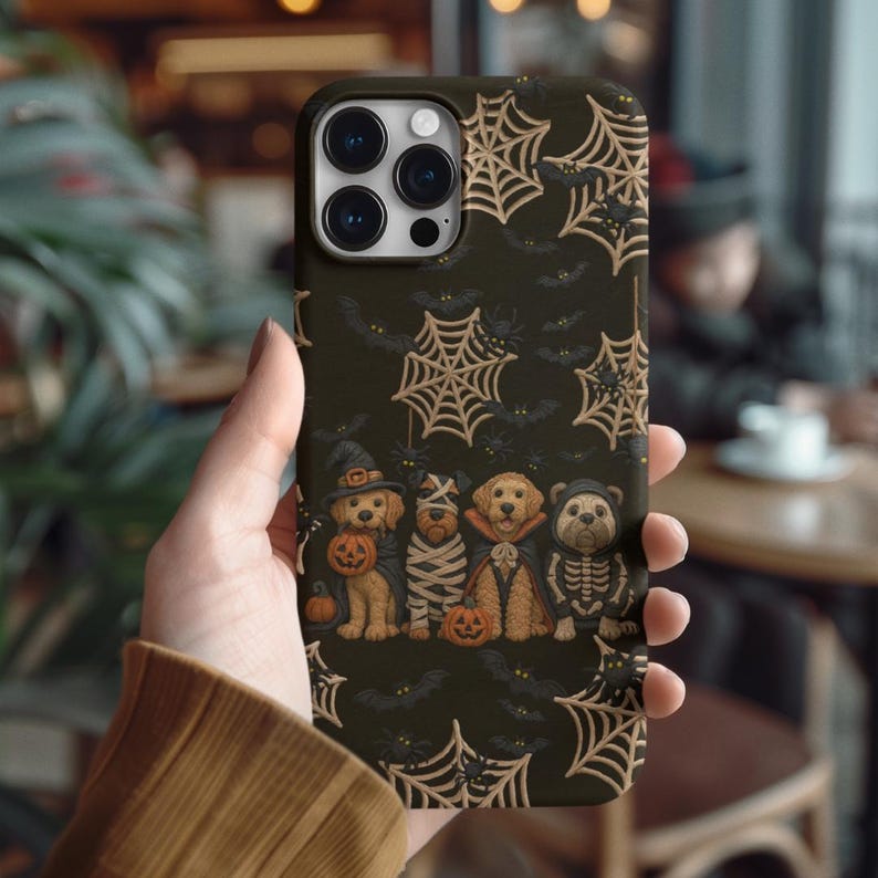 Halloween-themed phone case with four cute dogs in spooky costumes like mummy, skeleton and witch, surrounded by spiderwebs and bats.